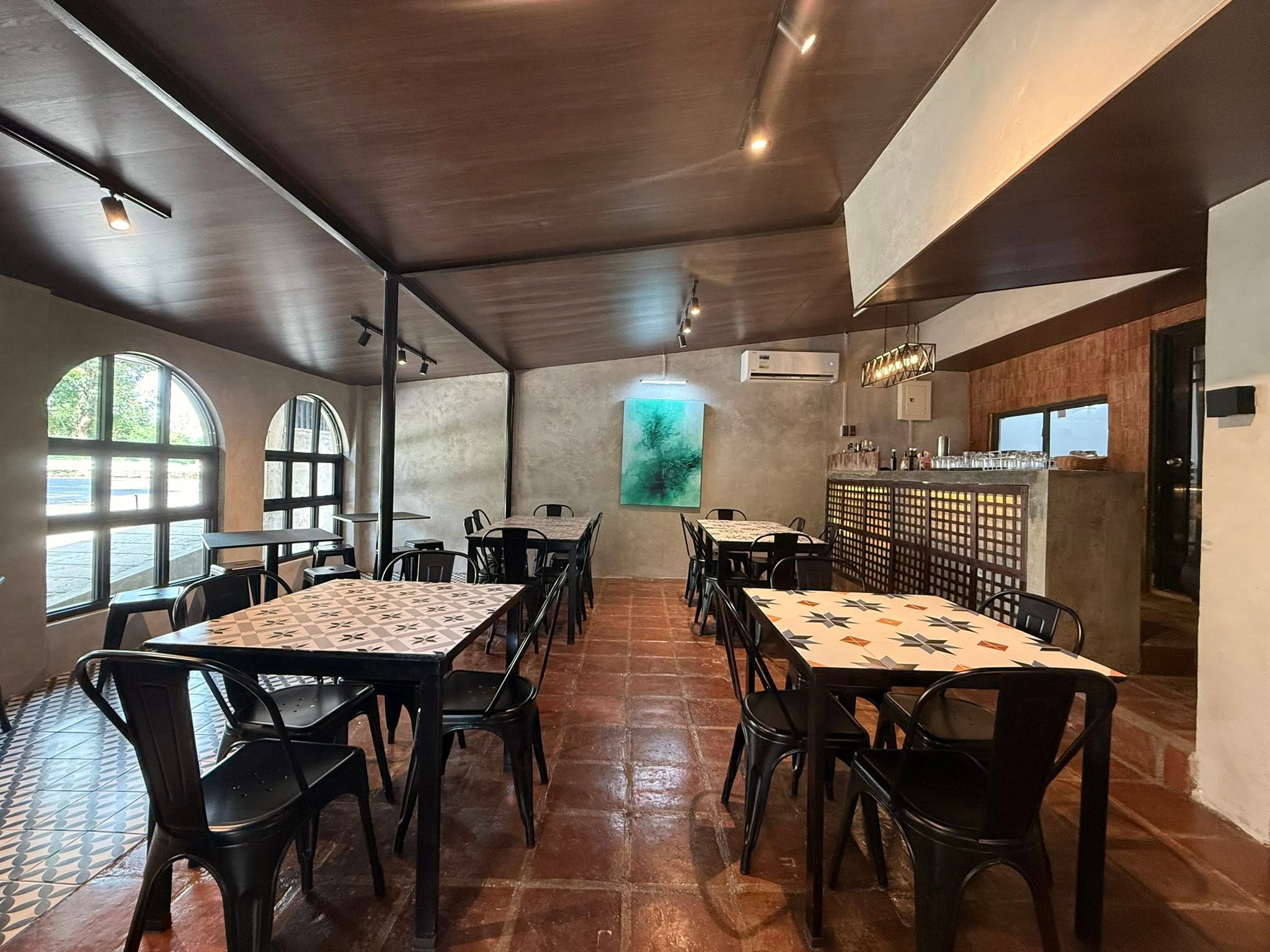 Dining room with black chairs, tiled tables and terracotta floors